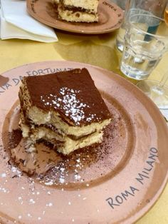 two pieces of cake sitting on top of a pink plate next to glasses and napkins