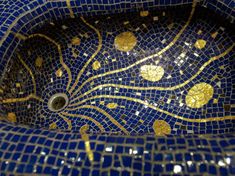 a blue and gold mosaic sink with golden circles on it's side, in the bathroom