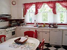 a kitchen with checkered flooring and red curtains