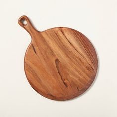 a round wooden cutting board on a white surface with a hook in the middle that is holding a knife