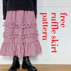 a woman standing in front of a wall wearing a red and white checkered skirt