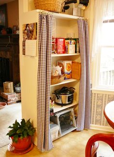 an open book shelf in the corner of a room with curtains pulled back to reveal it's contents