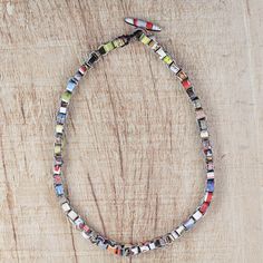 a multicolored beaded necklace is displayed on a wooden surface with a metal clasp