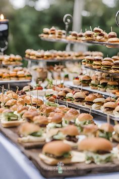 a table topped with lots of sandwiches on top of wooden trays filled with food