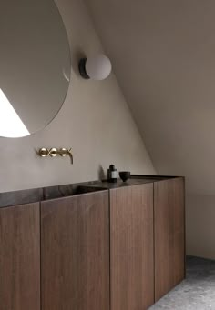 a bathroom with wooden cabinets and a round mirror