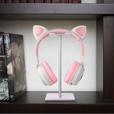 a pair of pink cat ears headphones on a stand in front of some books