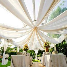 an outdoor wedding venue with white draping and tables