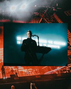 a man standing in front of a large screen with a microphone on it's side