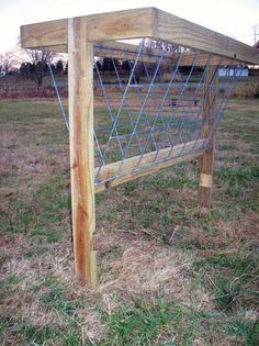 a wooden frame with blue wire on it in the grass near a fence and some trees