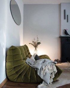 a green bean bag chair sitting on top of a hard wood floor next to a white wall