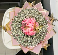 a bunch of money with pink flowers and butterflies around it on top of a toilet