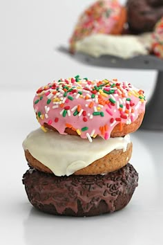 three donuts with frosting and sprinkles stacked on top of each other