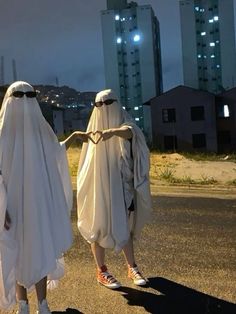 two people dressed in white walking down the street