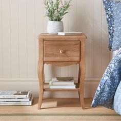 a nightstand with flowers on it next to a bed