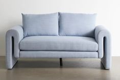 a light blue couch sitting on top of a cement floor next to a white wall