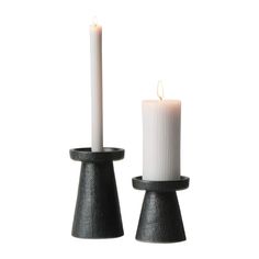 two candles are sitting next to each other on a white background, one is black and the other is white