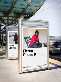 a man sitting on top of a chair next to a bus stop sign with the word fierce optimist in front of him