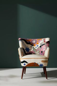 an upholstered chair in front of a green wall