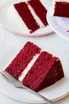 two slices of red velvet cake with white frosting on plates next to each other