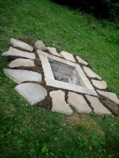 an open fire pit in the middle of a grassy area with rocks and grass around it