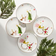 three plates with christmas designs on them next to pine branches