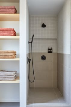 a bathroom with shelving and towels on the shelves in front of the shower head