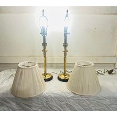 two lamps sitting on top of a bed next to each other