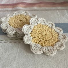 two crocheted flowers sitting on top of a bed