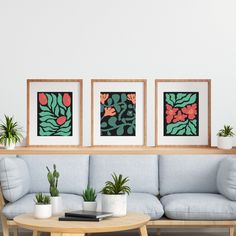 three framed pictures hang on the wall above a couch in a living room with potted plants