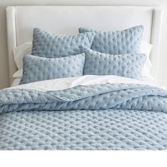 a bed with blue comforters and pillows on it