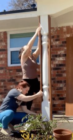 two women are doing tricks on the side of a house while another woman is reaching up