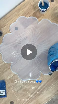 a clear flower shaped object sitting on top of a wooden table next to blue cups