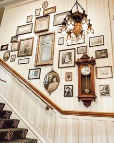 a staircase with many framed pictures on the wall and a clock mounted to the wall