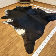 a black and white cowhide rug is on the floor next to a measuring tape