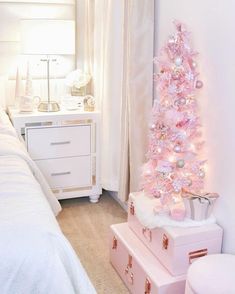 a pink christmas tree in a bedroom next to a white toilet and dresser with drawers