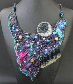 "This one-of-a-kind, Van Gogh styled bib necklace is a show stopper with its \"Starry Starry Night\" theme!       A wide variety of glass stars and fully beaded moon adorn its darkly rich fabric base. Long, deep blue though dark purple bugle beads support asymmetrical silver star fringe. All is stunningly edged with myriad Czech glass seed beads.      Hand strung bugle beads, glass seed beads, and AB blue violet chain make this beauty fully adjustable to 22\"; the clasp is gold filled. All is carefully backed with soft black Ultra Suede.       This uniquely elegant neck piece will definitely win prizes when worn. Its song is dark and luxurious." Artistic Handmade Necklaces For Party, Artisan Purple Necklaces For Festivals, Artisan Purple Necklace For Festivals, Starry Starry Night Theme, Starry Night Theme, Beaded Moon, Starry Starry Night, Night Theme, Beaded Work