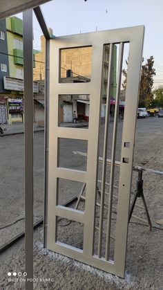 an open metal door on the side of a road next to a parking lot with buildings in the background