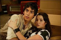 the young man and woman are posing together in front of cardboard boxes with their arms around each other