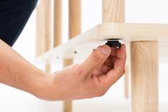 a person is holding something in their hand near a wooden structure with white paint on it