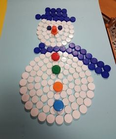 a snowman made out of buttons sitting on top of a blue table with yellow and white dots