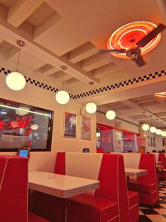 the interior of a fast food restaurant with red booths and checkered flooring on the walls