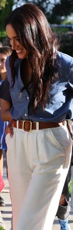 a woman in white pants and blue shirt walking