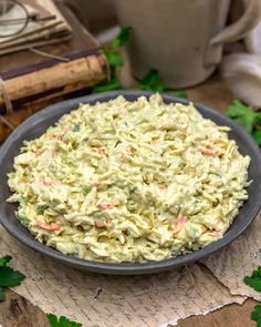 a bowl filled with coleslaw on top of a table next to a book