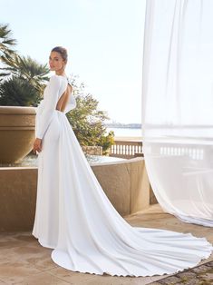 a woman in a white wedding dress standing on a balcony