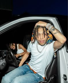 a man with dreadlocks sitting in the driver's seat of a car