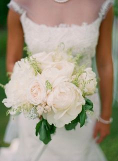 white flowers and greenery in a square vase on a pink tableclothed table