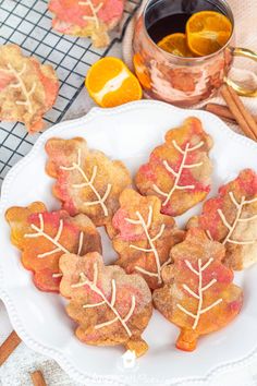 some cookies are on a white plate with oranges and cinnamon sticks next to it