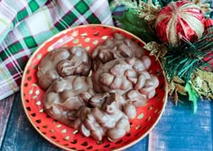 a red bowl filled with chocolate covered candies on top of a table next to christmas decorations