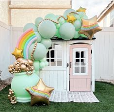 a balloon arch with balloons and stars on it in front of a small house decorated for a birthday party