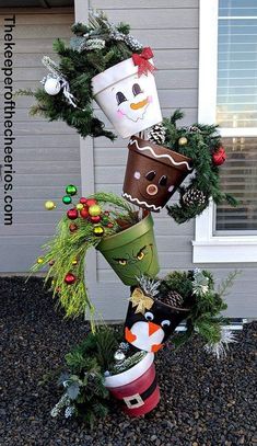 some christmas decorations are stacked on top of each other in front of a house with a snowman